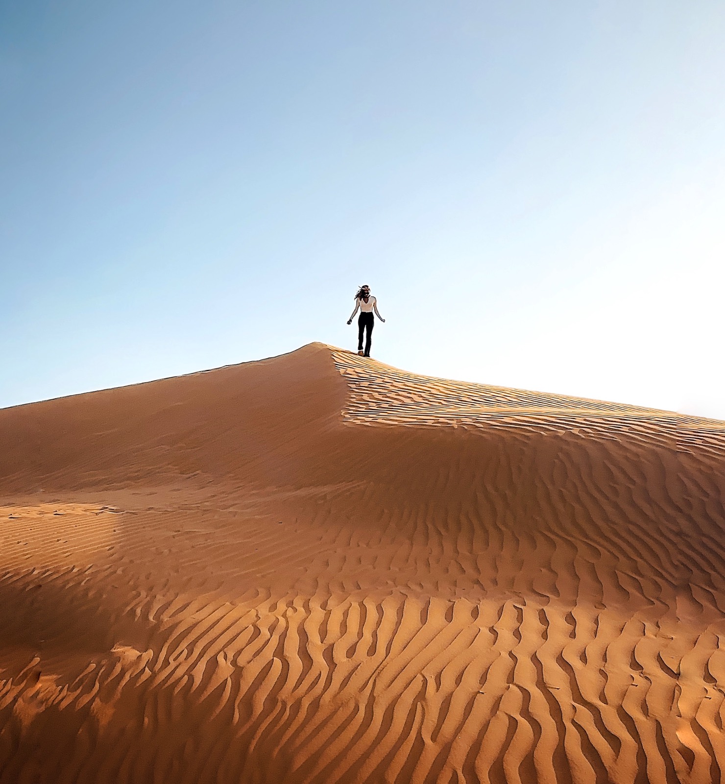 A figure walking across a desert dune